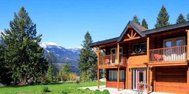 A wooden house with a mountain backdrop under a clear blue sky.
