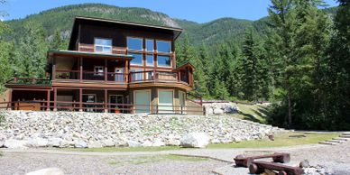 Modern cabin in the mountains surrounded by trees and rocks.