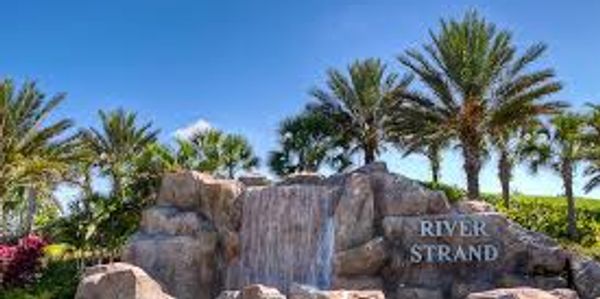Waterfall feature with palm trees and 'River Strand' sign.