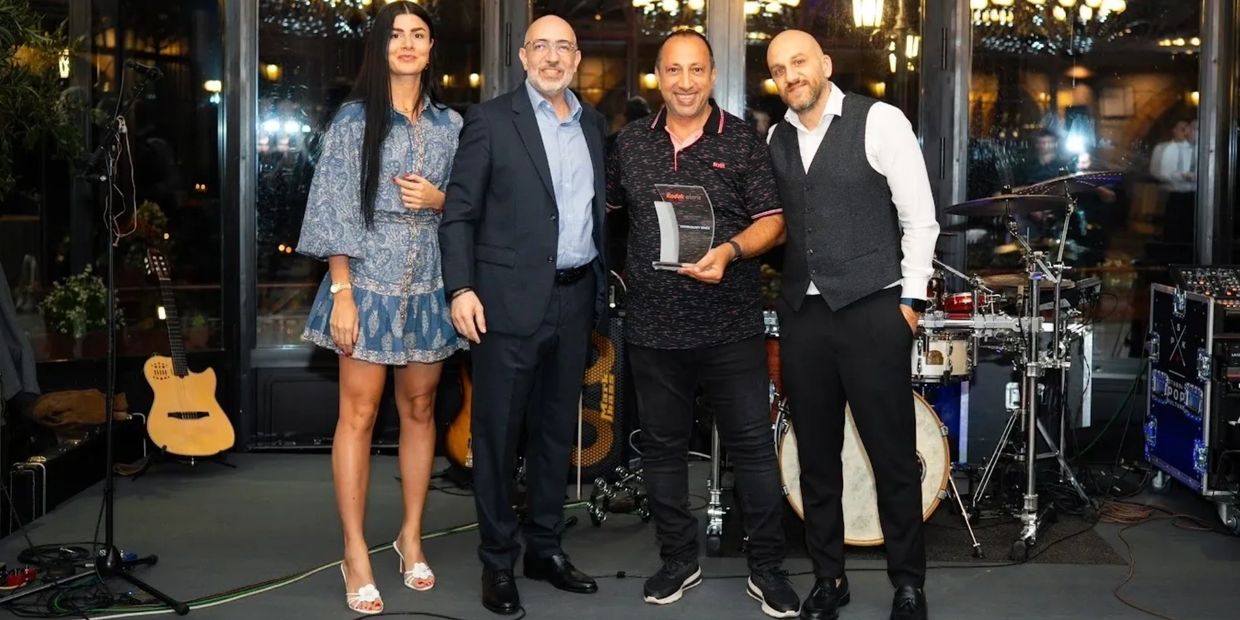 Four people posing together indoors, one holding an award.
