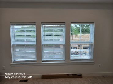Empty room with three windows and blinds.