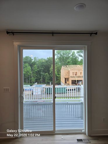 View through sliding glass door showing construction and trees.