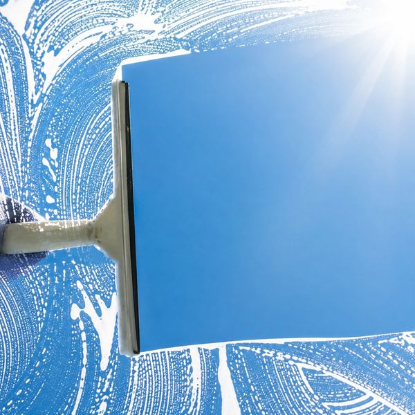 Window being cleaned with a squeegee on a sunny day.