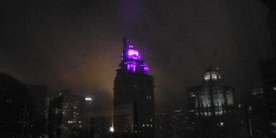 Chicago skyline at night. Purple glow from atop a domed skyscraper as seen from Downtown Marriott.