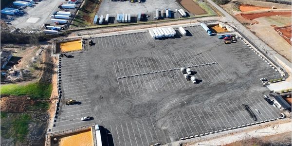 A large empty parking lot with some trucks and construction areas around.