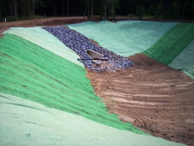 A newly constructed drainage channel with green erosion control matting on slopes.