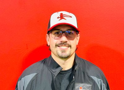 Man wearing a cap and glasses against a red background.