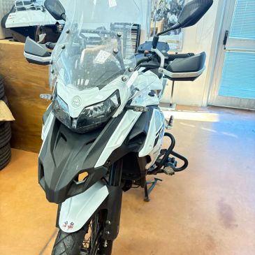 Front view of a white adventure motorcycle with a windshield in a garage.