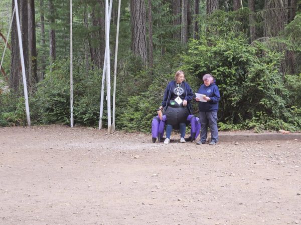 Two women outdoors reviewing a paper in a forest setting.
