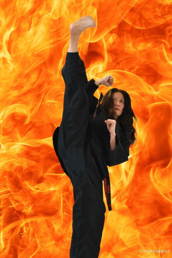 Martial artist performing a high kick against a fiery background.