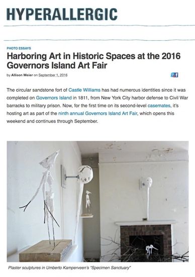 Exhibition space with sculptural art and a fireplace in a historic setting.