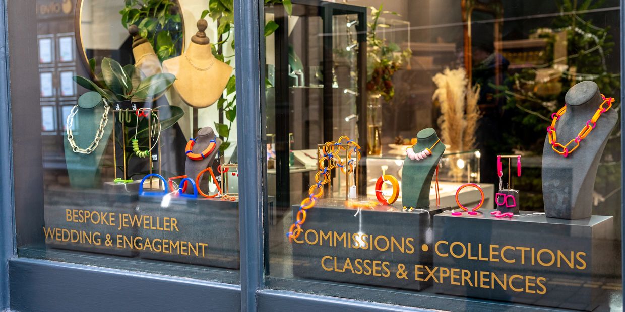 Colorful handmade jewelry displayed in a boutique window.