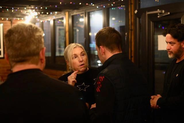 Four adults engaged in a serious conversation indoors.