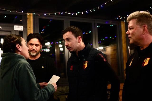 Four people having a serious discussion indoors at night.