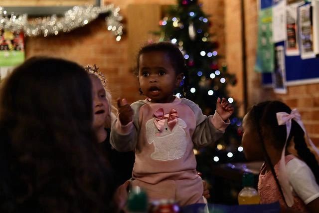 Children gathered near a Christmas tree decorated with lights.