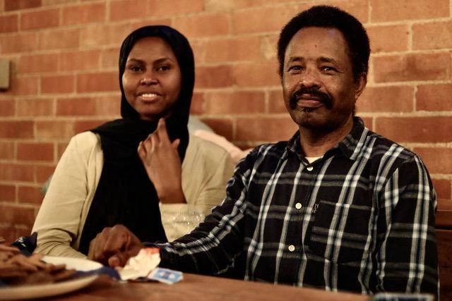 Two people sitting at a table, smiling.