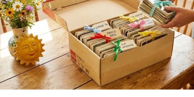 Box of organized fabric bundles tied with colorful ribbons on a wooden table.