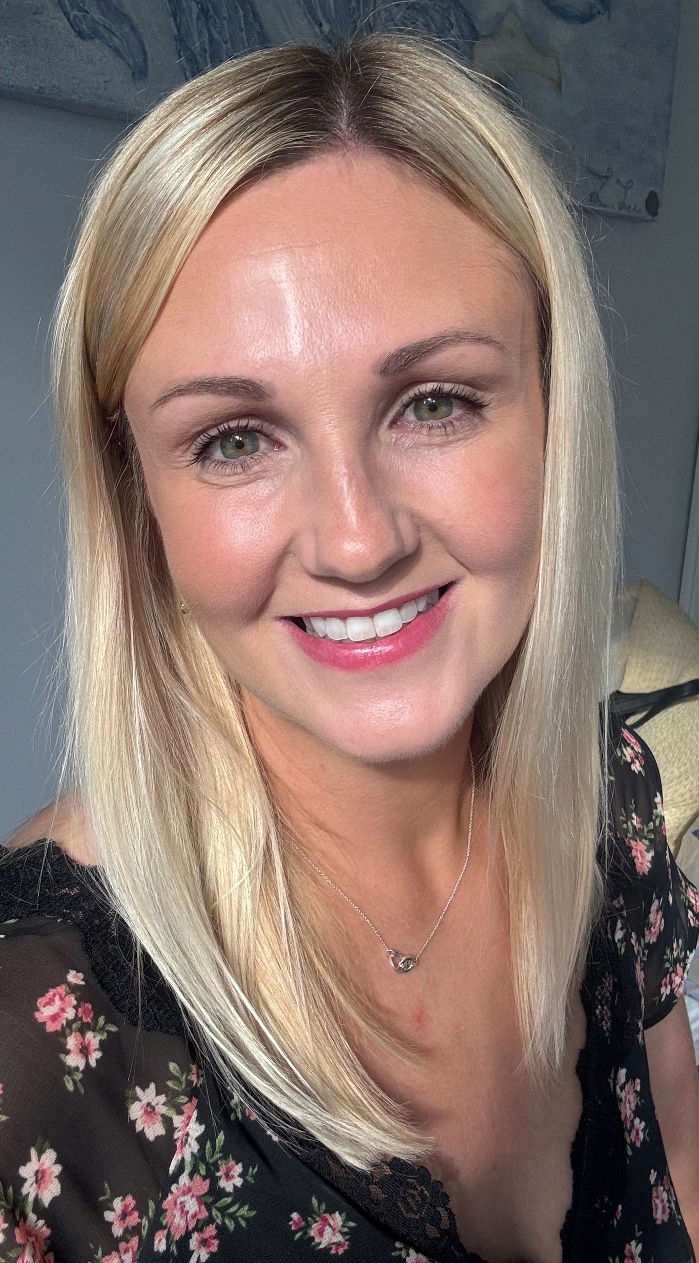Smiling woman with blonde hair and floral dress.
