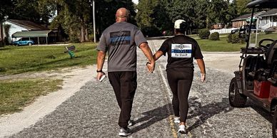 Couple holding hands walking down a road in a neighborhood.