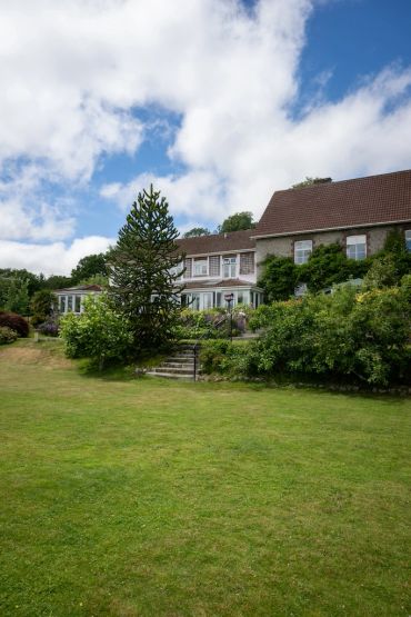 Large house with garden and steps under a blue sky.