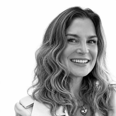 Black and white portrait of a smiling woman with wavy hair.
