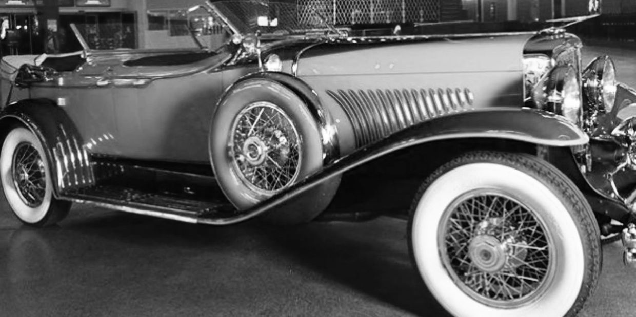 Classic vintage car with whitewall tires and intricate wire-spoke wheels.