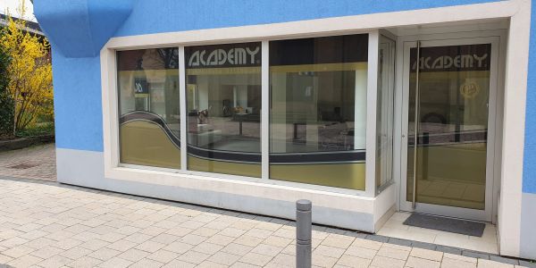 Fassade eines blauen Gebäudes mit der Aufschrift "ACADEMY".