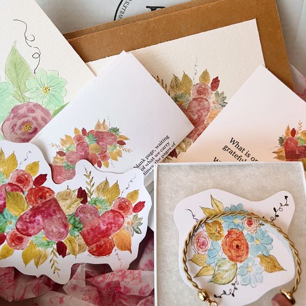 Hand-painted floral cards and a bracelet with a floral tag.