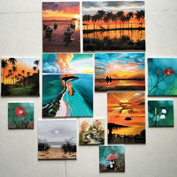 A collection of vibrant landscape and nature paintings arranged on a floor.