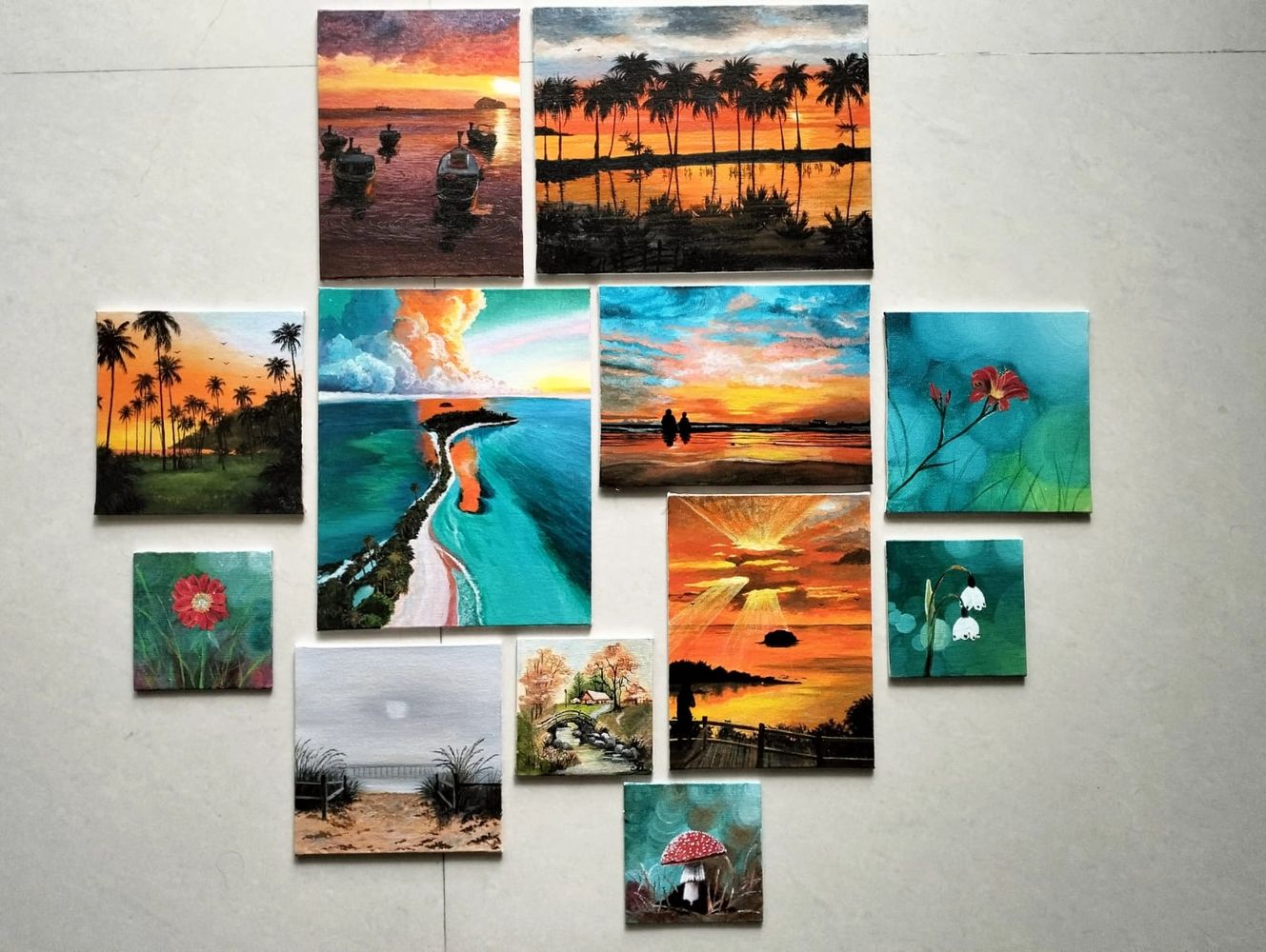 A collection of vibrant landscape and nature paintings arranged on a floor.