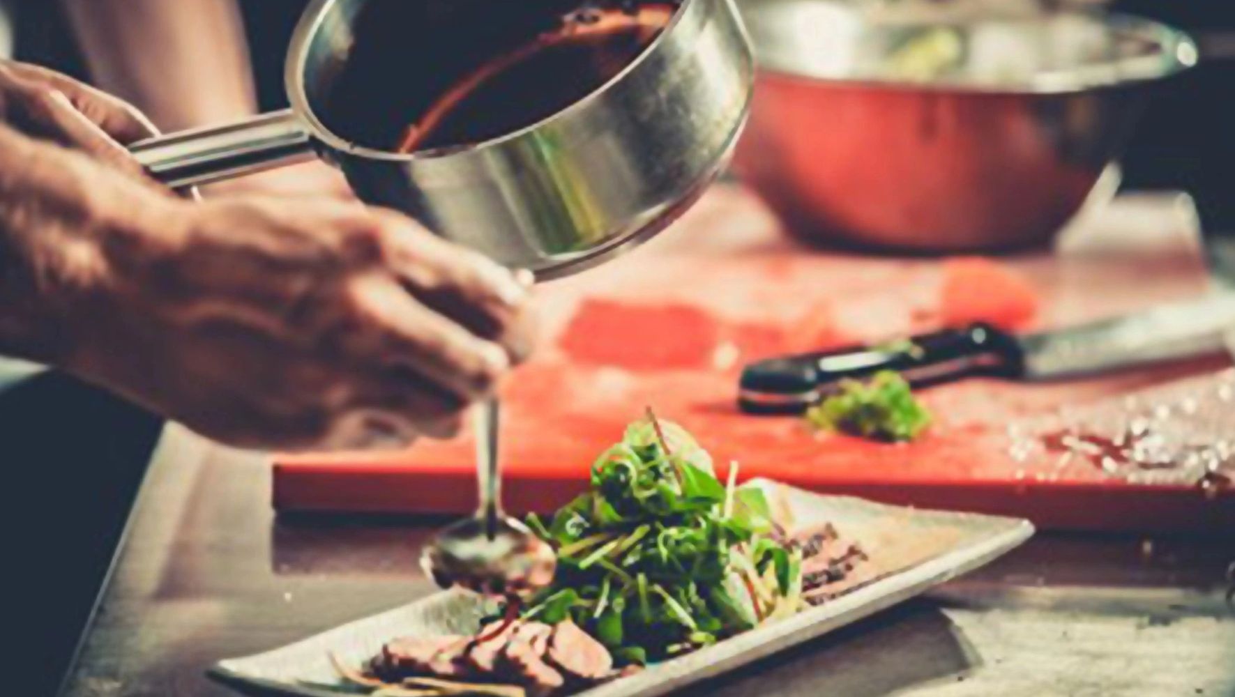 Hand pouring sauce over a plate of meat.