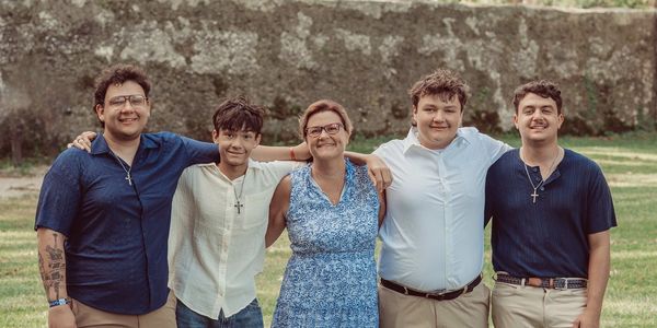 A happy family photo with four young men and a woman standing outdoors.