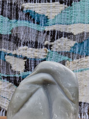 Abstract stone sculpture with textured fabric backdrop.