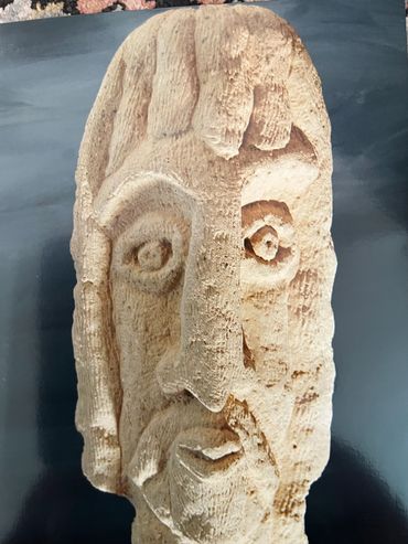 Carved stone sculpture of a face with abstract features.