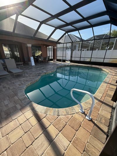 A small indoor pool under a glass roof with lounge chairs nearby.