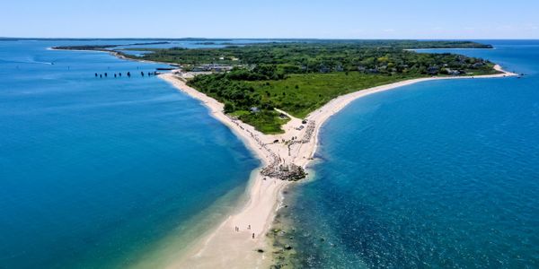 A narrow sandy peninsula surrounded by clear blue waters on both sides.