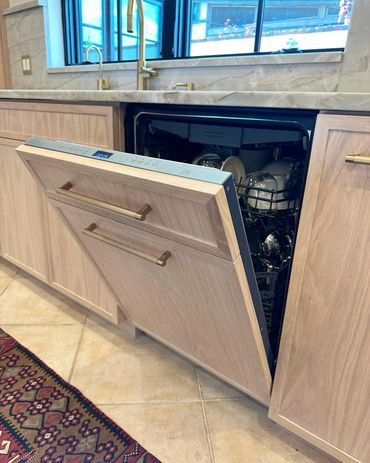 Open built-in dishwasher in a modern kitchen with wooden cabinetry.