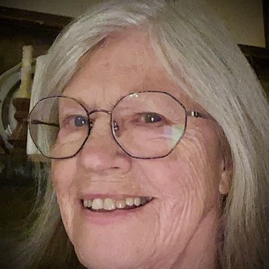 Smiling elderly woman with glasses and gray hair.