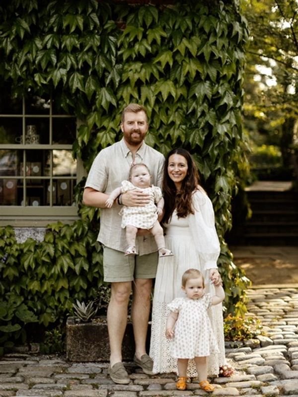 Family of four posing outdoors with greenery.