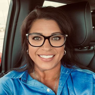Woman with glasses smiling inside a car.