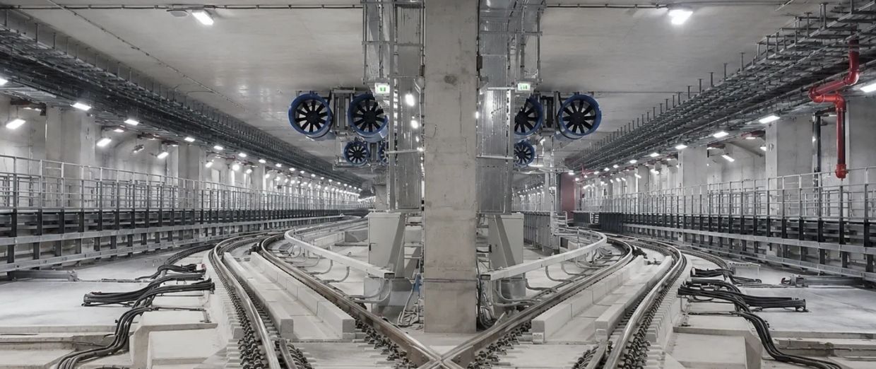Symmetrical underground railway tracks with mechanical fans above.