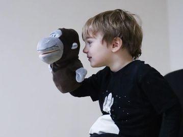 Mini Actors playing with a monkey hand puppet.