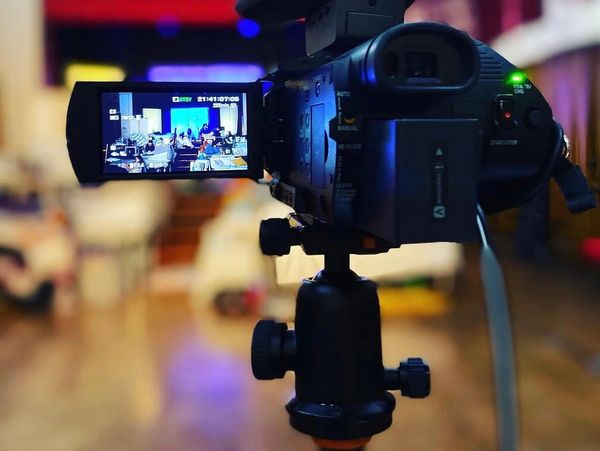 A video camera on a tripod recording an indoor event.