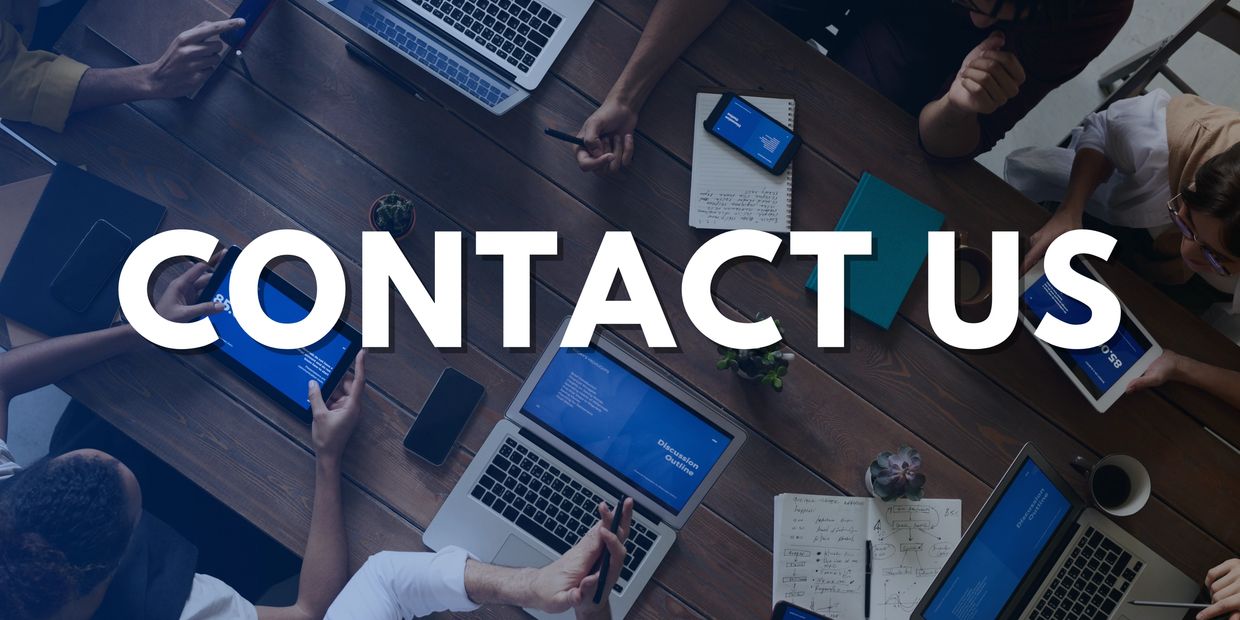 People collaborating at a wooden table with digital devices and 'CONTACT US' text overlay.