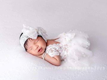 a cute new born baby in a white attire 
