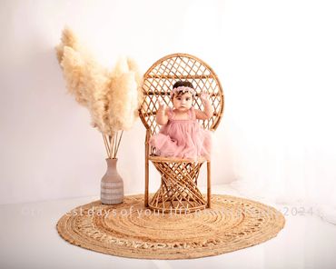 a cute little baby girl sitting on a chair 