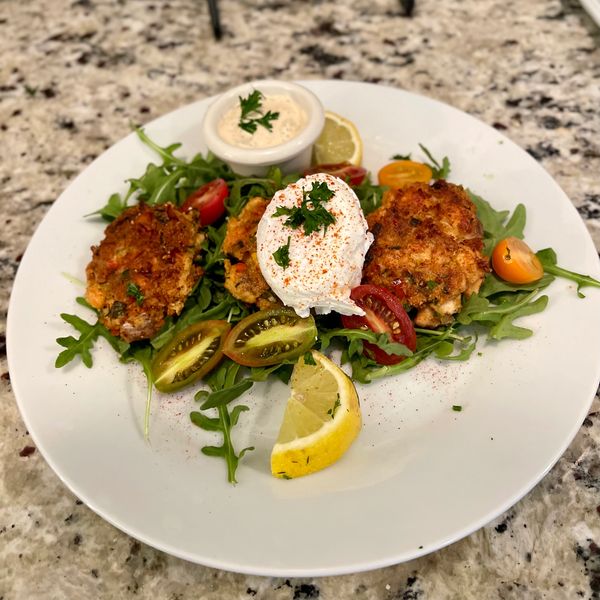 Salmon cakes with poached egg on a bed of arugula