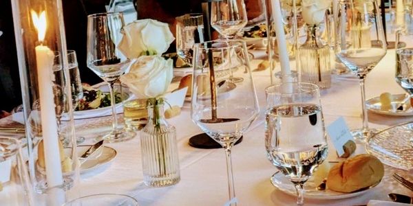 Elegant dinner table set with candles, white roses, glassware, and plated salads.