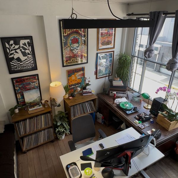 Cozy workspace with vinyl records, vibrant posters, and a bright window.