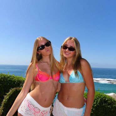 Two young women posing at the beach in bikinis.
